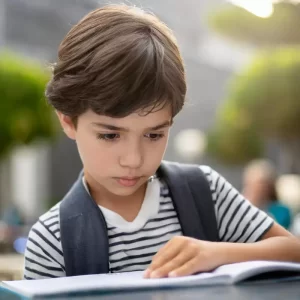 Un giovane studente con disprassia scrive sul suo quaderno, affrontando le sfide legate alla coordinazione motoria e alla disprassia verbale durante il processo di apprendimento.